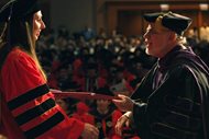 John Marshall Law School professor Robert Jay Nye hands a diploma to a recent graduate.