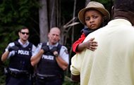 A Haitian boy holds onto his father as they approach an illegal crossing point, staffed by Royal Canadian Mounted Police officers, from Champlain, N.Y., to Saint-Bernard-de-Lacolle, Quebec on Monday. Seven days a week, 24-hours a day people from across the globe are arriving at the end of a New York backroad so they can walk across a ditch into Canada knowing they will be instantly arrested, but with the hope the Canadian government will be kinder to them than the United States. 