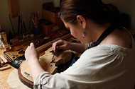 Sonja St. John inserts a note in one of her handmade violins at her workshop in Neenah, Wis., on April 27. The message reads, “In honor of past, present and future souls of courage and wisdom.” St. John writes a different message for each violin she makes, always keeping her brother, Jon St. John, and other veterans in mind. 