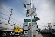A truck passes a red-light photo enforcement sign that is placed below a red light camera at the intersection of Route 1 and Franklin Corner Road in Lawrence Township, N.J. on  Dec. 16, 2014. Red-light cameras are widely hated, but a new study says getting rid of them can have fatal consequences. Traffic deaths from red-light-running crashes go up by nearly a third after cities turn off cameras designed to catch motorists in the act, according to a study by the Insurance Institute for Highway Safety. The institute is funded by auto insurers. 