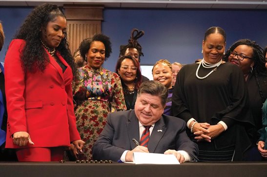 Illinois Gov. J.B. Pritzker signs into law the Paid Leave For All Workers Act as Illinois House Speaker pro-tem Jehan Gordon-Booth, from left, Lt. Gov. Juliana Stratton and Senate Majority Leader Kimberly Lightford watch Monday in Chicago.