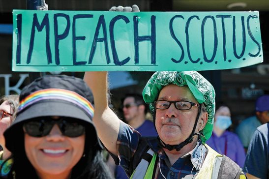 As reactions rocked the country after the U.S. Supreme Court ended constitutional protections for abortion, a spectator holds up an “Impeach SCOTUS” sign Sunday during the 51st Chicago Pride Parade in Chicago.